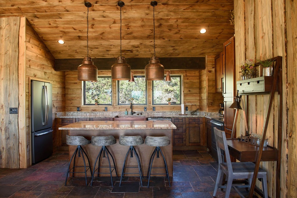 Rustic wooden lodge room with plush king bed, scenic mountain landscape view, warm earth tones, and elegant southwestern-inspired decor at mountain retreat