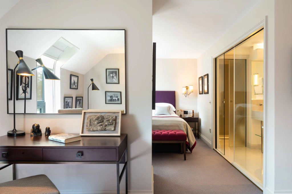 Elegant hotel room with plush white bedding, classic wood furnishings, soft neutral color palette, and refined traditional British architectural details