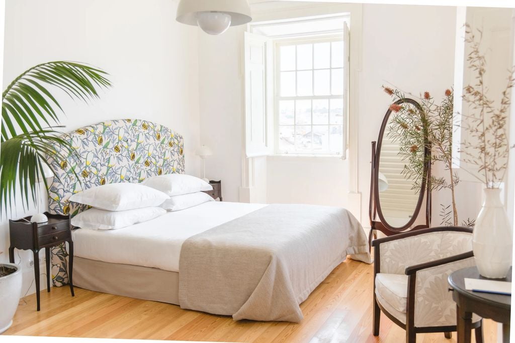 Bright minimalist hotel suite with sleek white walls, arched doorways, custom wooden furniture and Mediterranean-inspired decor and tile floor