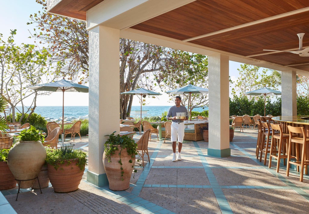 Elegant oceanfront hotel with white facade, swaying palm trees and manicured gardens, set against clear blue Florida sky and Atlantic waters