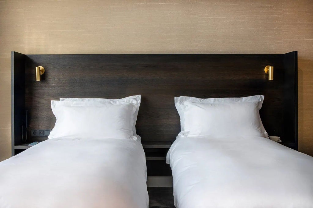 Elegant twin bed in luxurious Reylof Boutique Hotel room, featuring plush white linens, sophisticated decor, and soft ambient lighting in Belgium