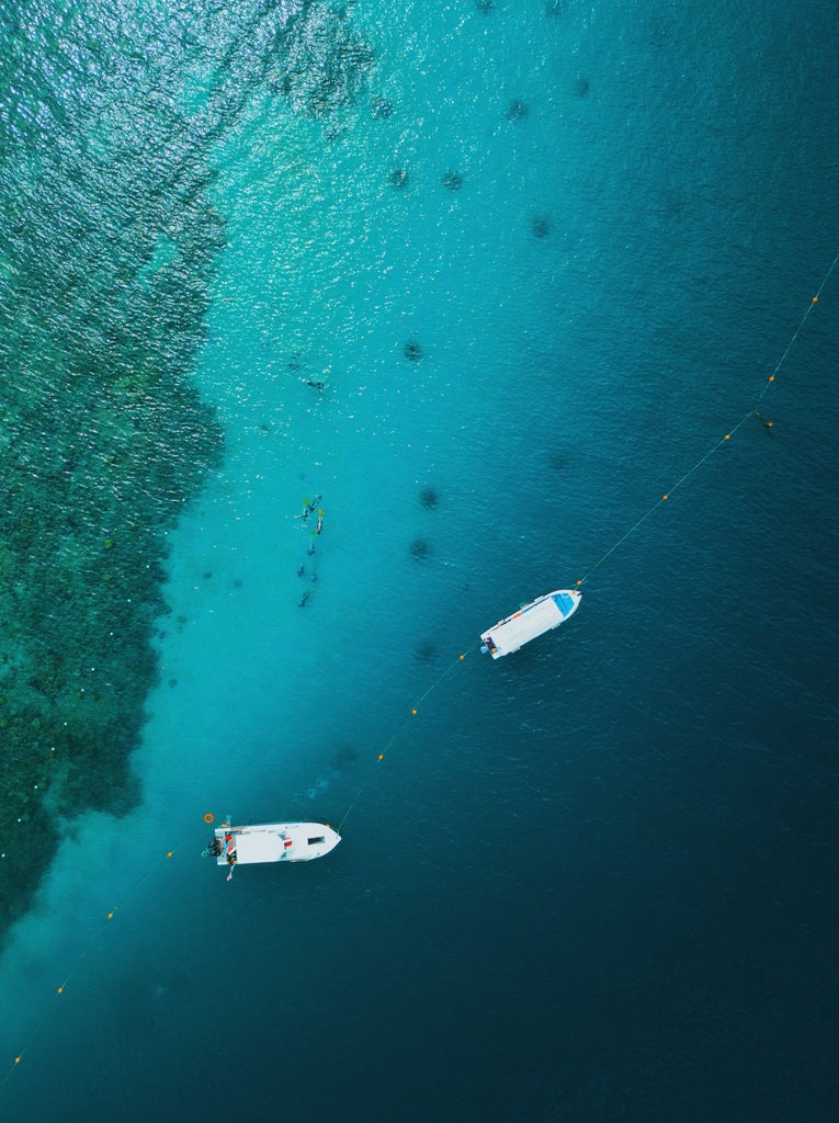 Luxurious speedboat gliding through turquoise waters near Phi Phi Bamboo Island, Thailand, with pristine white sandy beach and lush tropical landscape in background