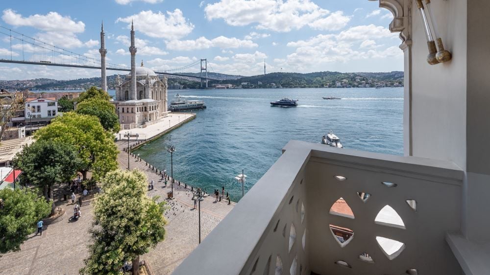 Luxurious boutique hotel overlooking Bosphorus Strait, featuring modern Turkish architecture with elegant white exterior and panoramic water views at sunset