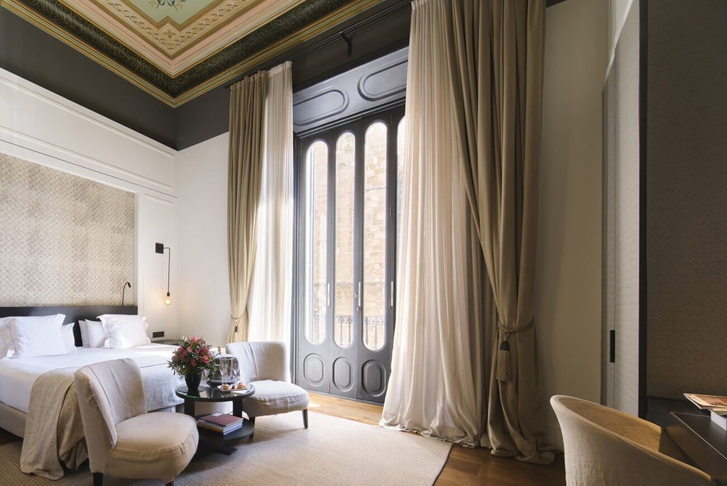 Elegant limestone boutique hotel with neoclassical facade, arched windows, and warm golden lighting at dusk in Palma de Mallorca's historic center