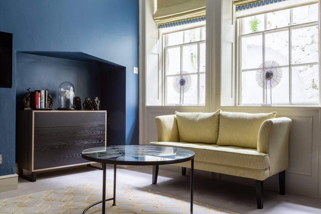 Elegant classic hotel room with cream walls, luxurious king bed, plush grey armchair, and soft lighting in a refined United Kingdom boutique setting