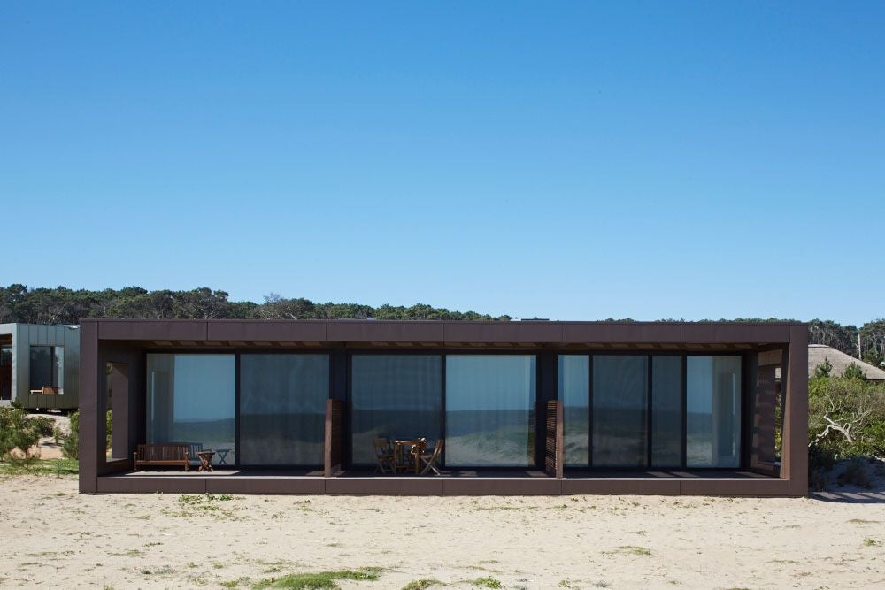 Minimalist wooden bungalow at Bahia Vik resort, nestled in sandy landscape with sleek design, ocean glimpse, and modern architectural elegance in José Ignacio, Uruguay