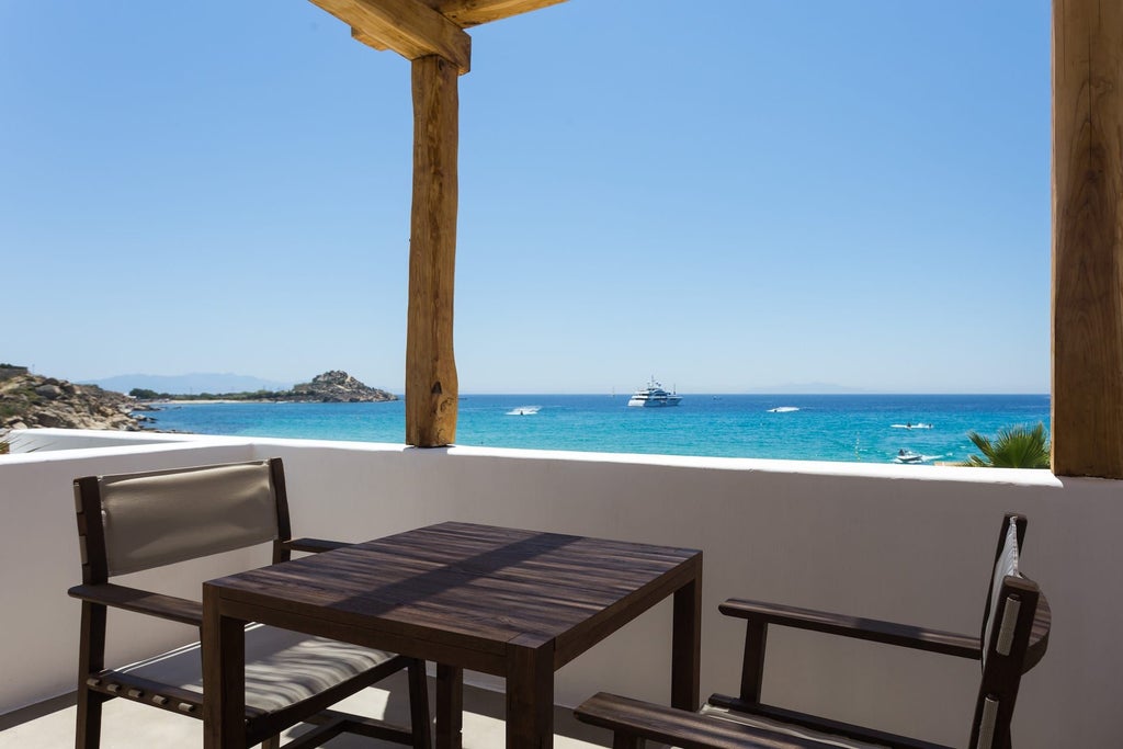 Luxurious white-themed superior sea view room at Branco Mykonos, featuring minimalist design, crisp linens, and panoramic Aegean Sea vista through large windows.