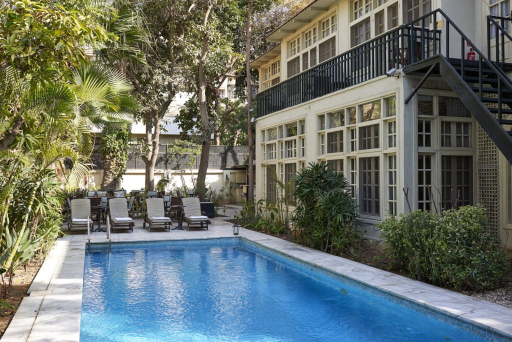 Elegant white colonial villa with arched windows and manicured garden, set against palm trees in upscale Maadi district, Cairo