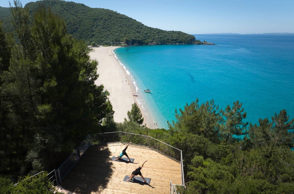 Luxurious seafront hotel with modern white architecture nestled against azure Grecian coastline, featuring minimalist design and panoramic ocean views