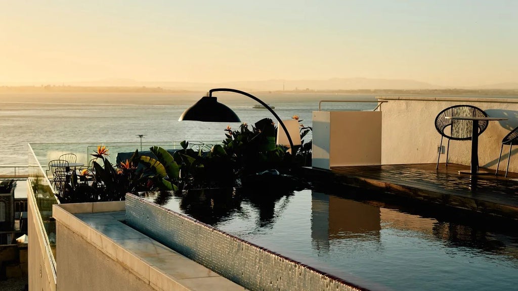 Panoramic sunset view of white-washed boutique Hotel in Alfama district, Lisbon, showcasing traditional Portuguese architecture with elegant terrace overlooking city rooftops