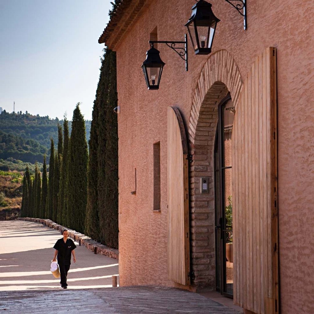 Rustic stone winery hotel nestled in golden vineyards, warm sunlight illuminating elegant Spanish architectural details and rolling countryside landscape