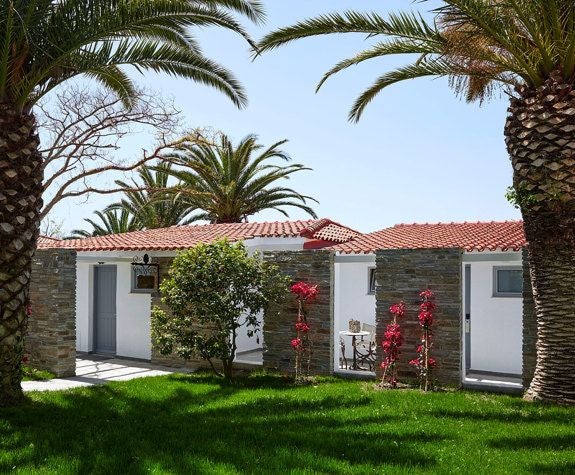 Luxurious garden-view bungalow at Eagles Palace, featuring elegant Mediterranean design with plush furnishings and lush greenery beyond large windows.