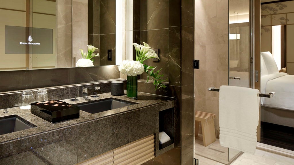 Japanese-style luxury hotel room with sliding paper screens, tatami floors, low wooden table and elegant dark wood furnishings bathed in warm light