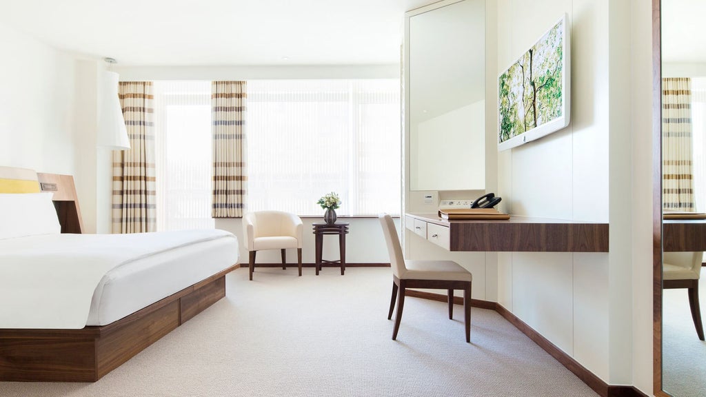 Luxurious COMO Suite with modern minimalist design, featuring elegant neutral tones, plush bedding, and sleek contemporary furnishings in London hotel room