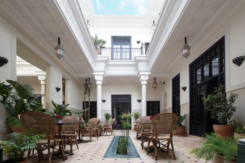 Elegant Moroccan riad with traditional archways and reflecting pool surrounded by orange trees and ornate tilework in tranquil courtyard