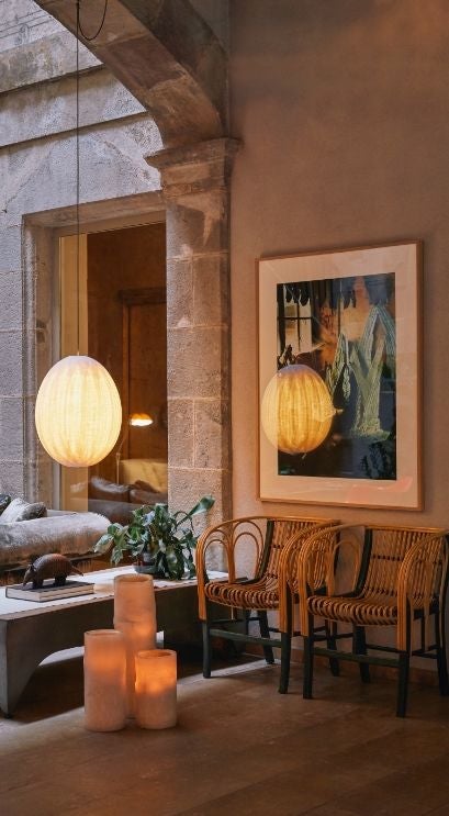 Historic Hotel Neri's elegant stone facade with wrought-iron balconies, illuminated archways, and ivy-covered walls in Barcelona's Gothic Quarter