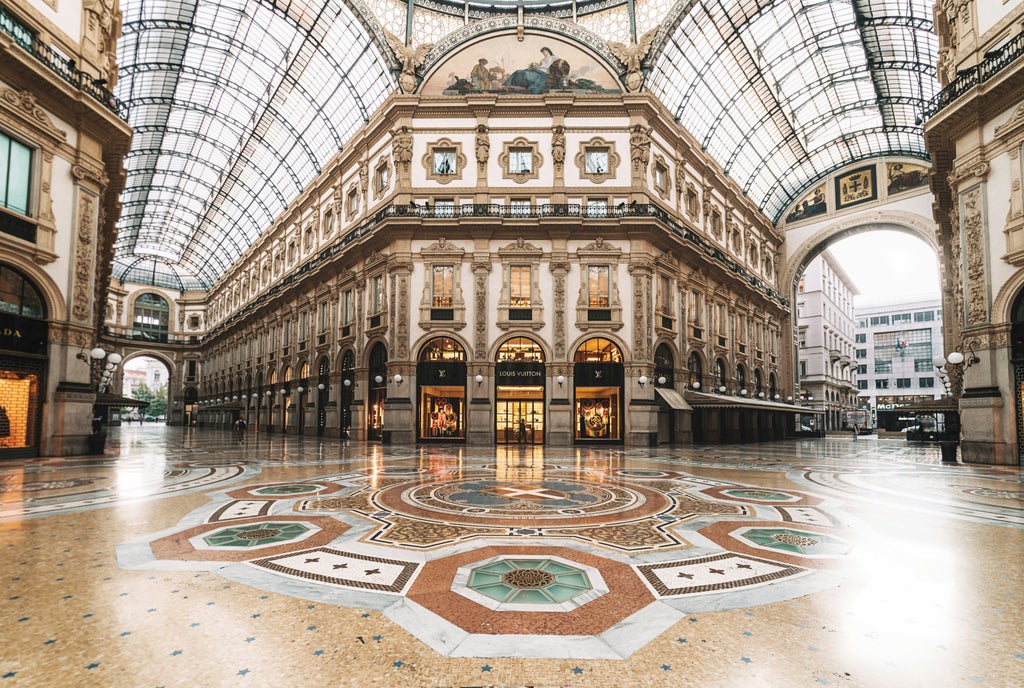 Elegant haute couture atelier in Milan with mannequins displaying designer gowns, fabric rolls and artisans at work tables