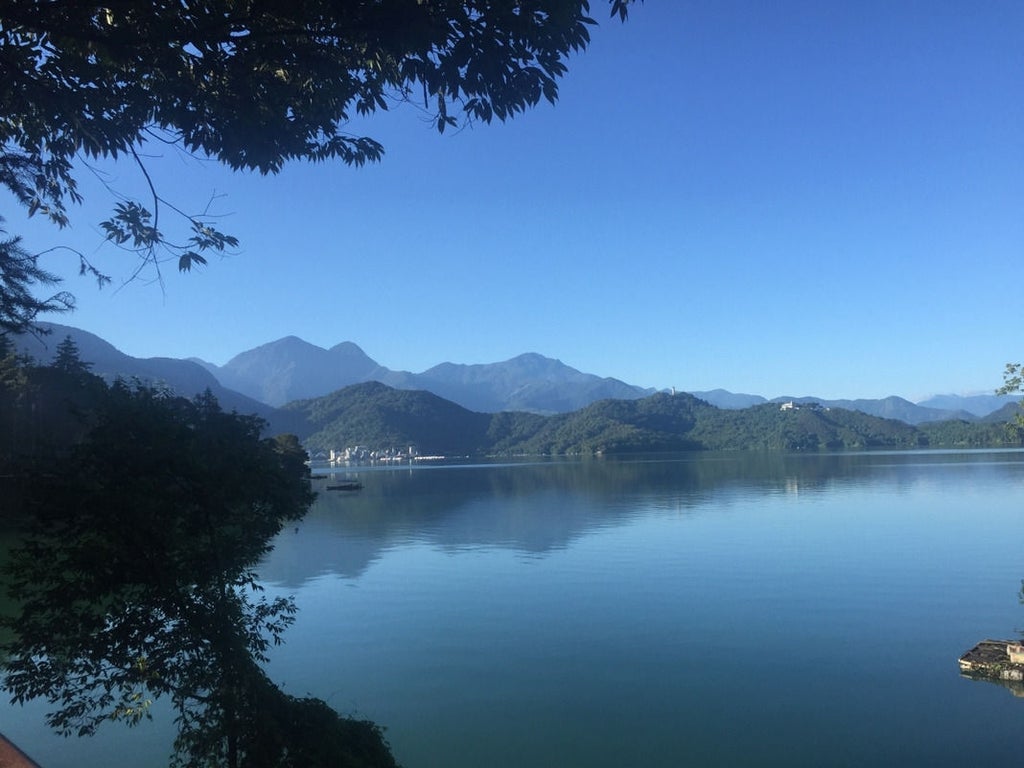 Elegant lakeside resort with modern facade and panoramic windows overlooking Sun Moon Lake, nestled among lush mountain scenery