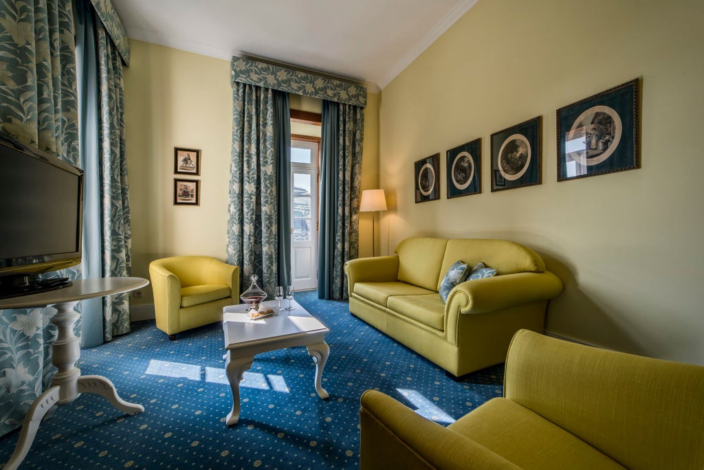 Elegant Deluxe Suite with wooden floors, plush king bed, vintage Portuguese decor, large windows overlooking scenic landscape in historic boutique hotel