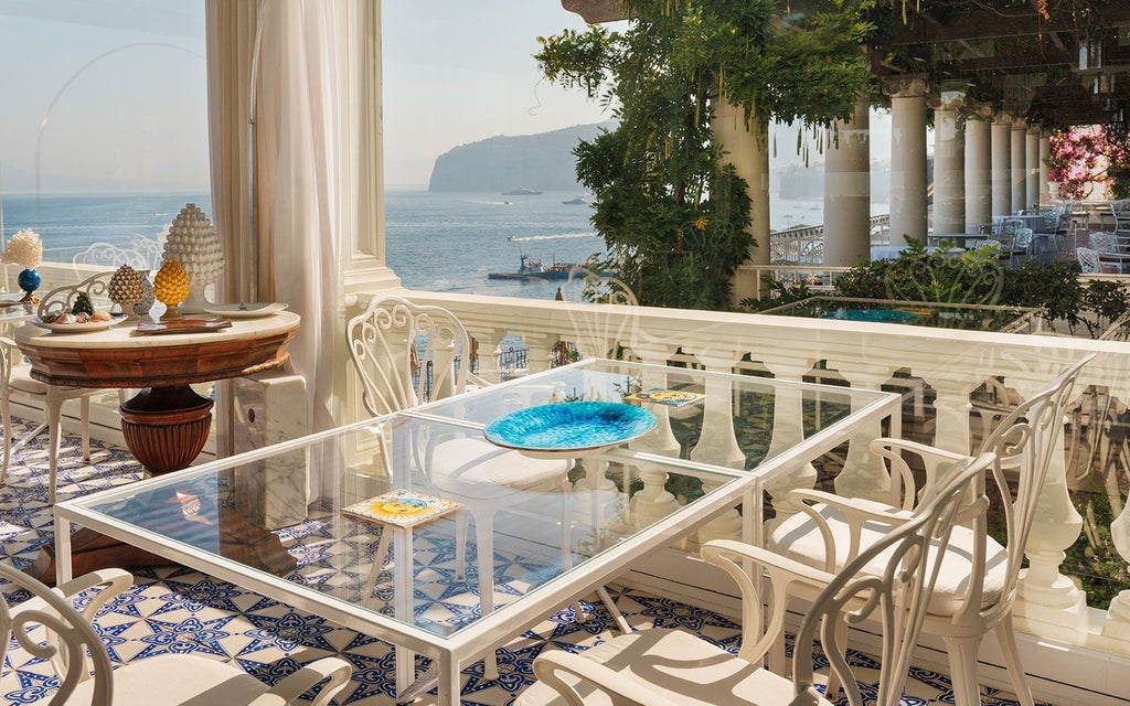 Luxurious cliff-side hotel overlooking azure Mediterranean waters, with elegant white façade and classic Italian architectural details in Sorrento