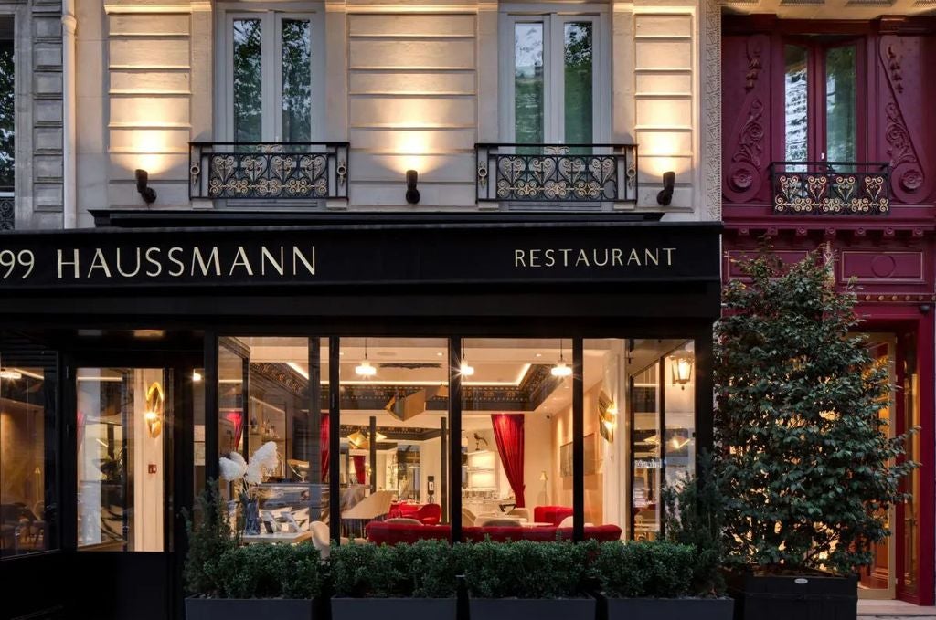 Elegant Parisian Hotel Bowmann with classic Haussmann-style stone facade, ornate balconies, and signature black iron railings in the afternoon sun.