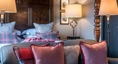 Elegant four-poster bed in a luxurious cottage suite at The Lygon Arms, adorned with plush textiles and traditional British countryside charm.