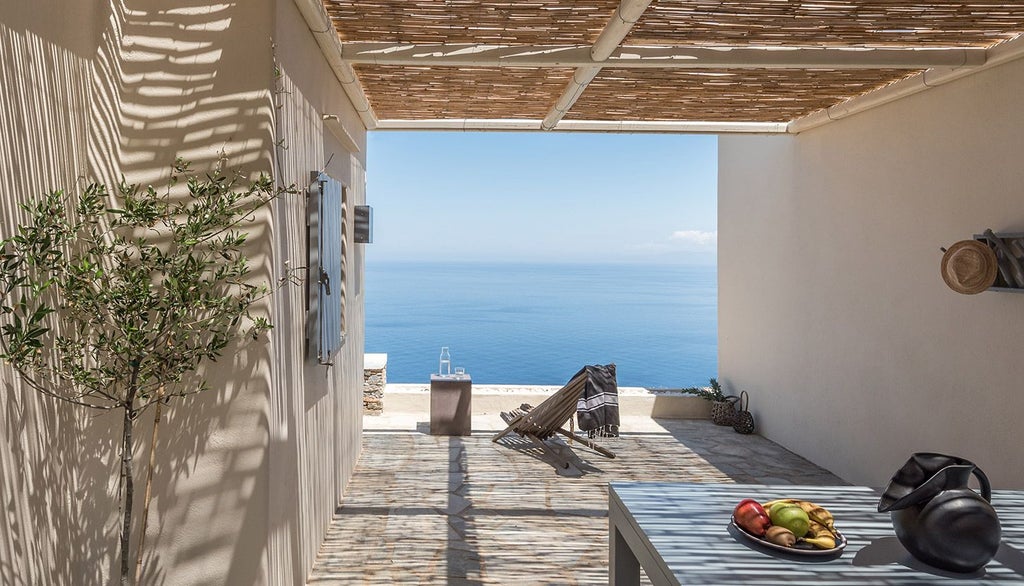 Minimalist white Greek hotel room with sleek design, featuring elegant bed, panoramic Aegean Sea view, and clean architectural lines at Verina Astra in Sifnos