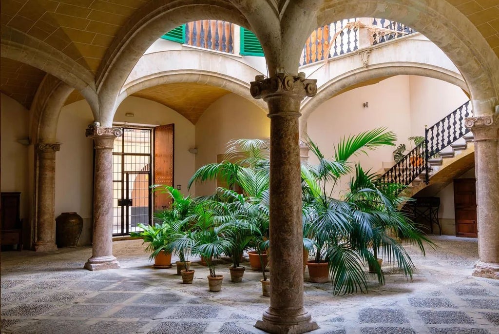 Historic luxury hotel exterior in Palma, Spain with stone facade, arched windows, and elegant Mediterranean architectural details at golden hour