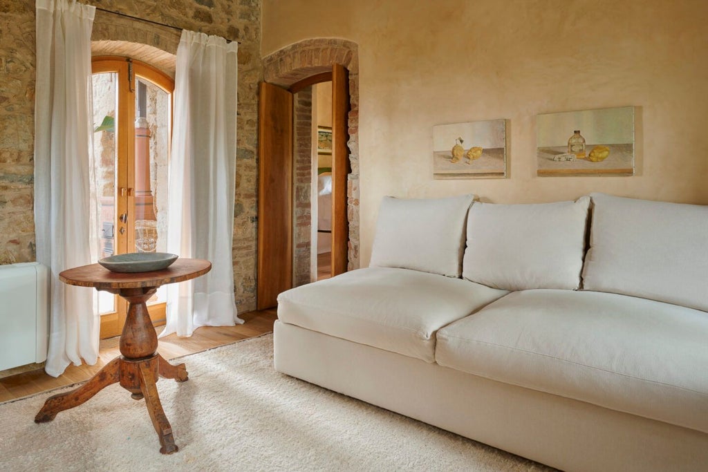 Elegant Tuscan suite with rustic stone walls, plush white bedding, and sweeping countryside views at Castello di Vicarello's luxurious Mezzatorre accommodation