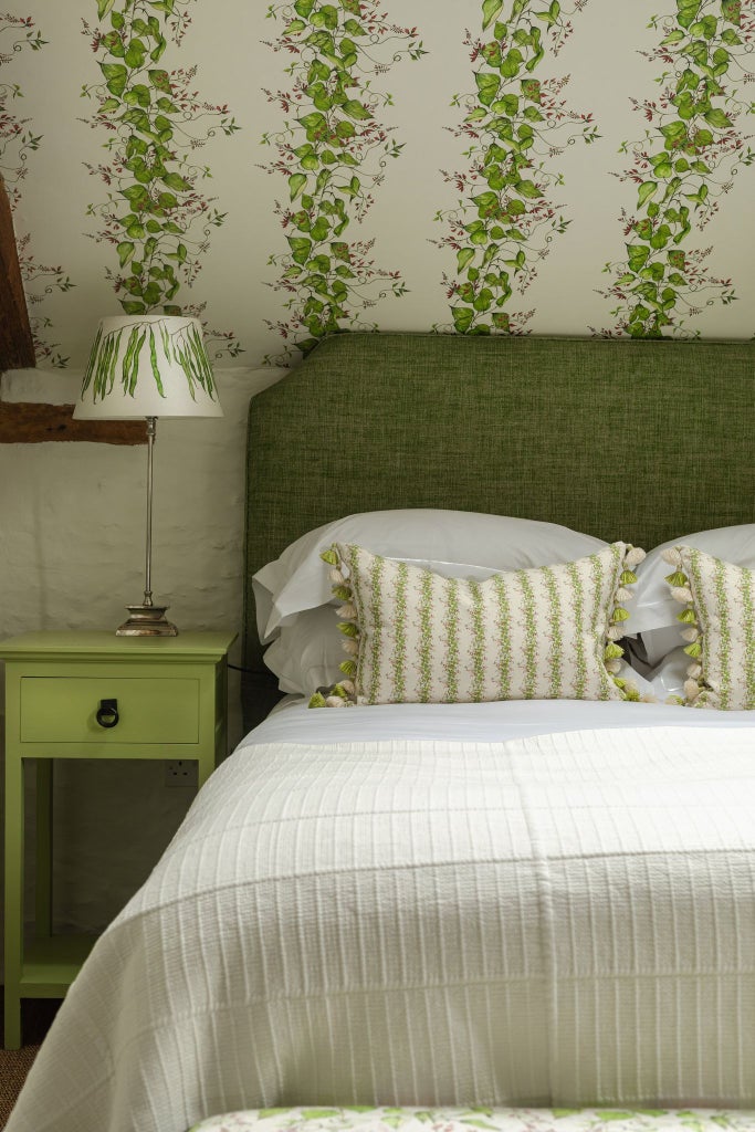 Rustic, elegant gardener's cottage bedroom with plush white bedding, herbal-themed decor, and soft natural light streaming through cottage windows