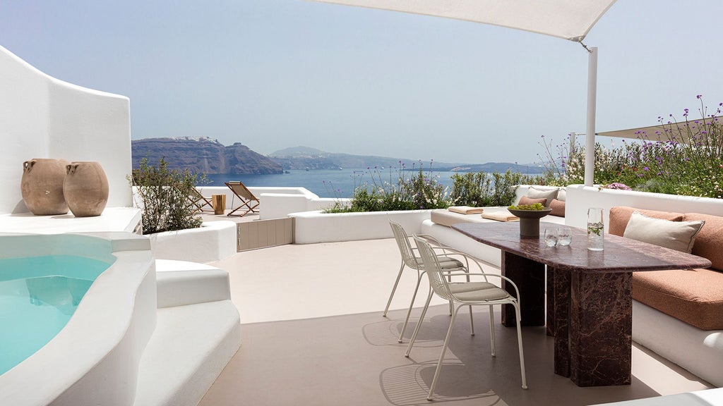 Luxurious two-bedroom suite with white-washed walls, minimalist design, private pool overlooking Santorini's caldera and azure Aegean Sea at sunset.