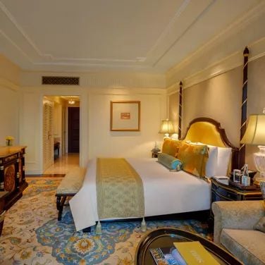 Opulent executive suite at scenset palace hotel, featuring elegant cream-toned decor, plush king bed, panoramic city views, and sophisticated contemporary Indian design elements