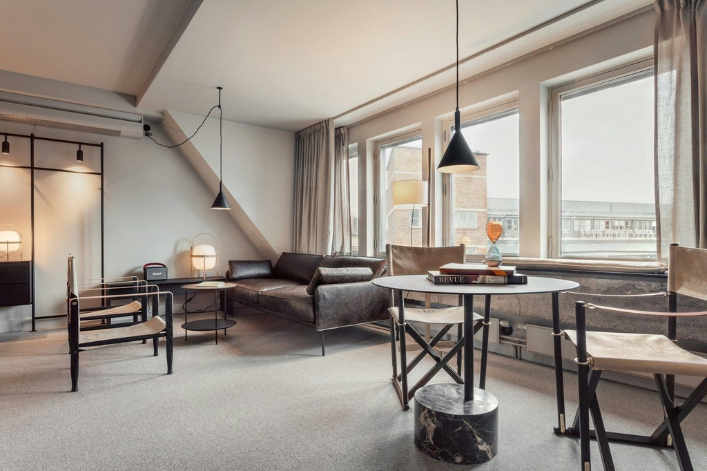 Minimalist Scandinavian hotel studio with sleek gray design, floor-to-ceiling windows, modern furnishings, and soft neutral color palette in urban Nordic style