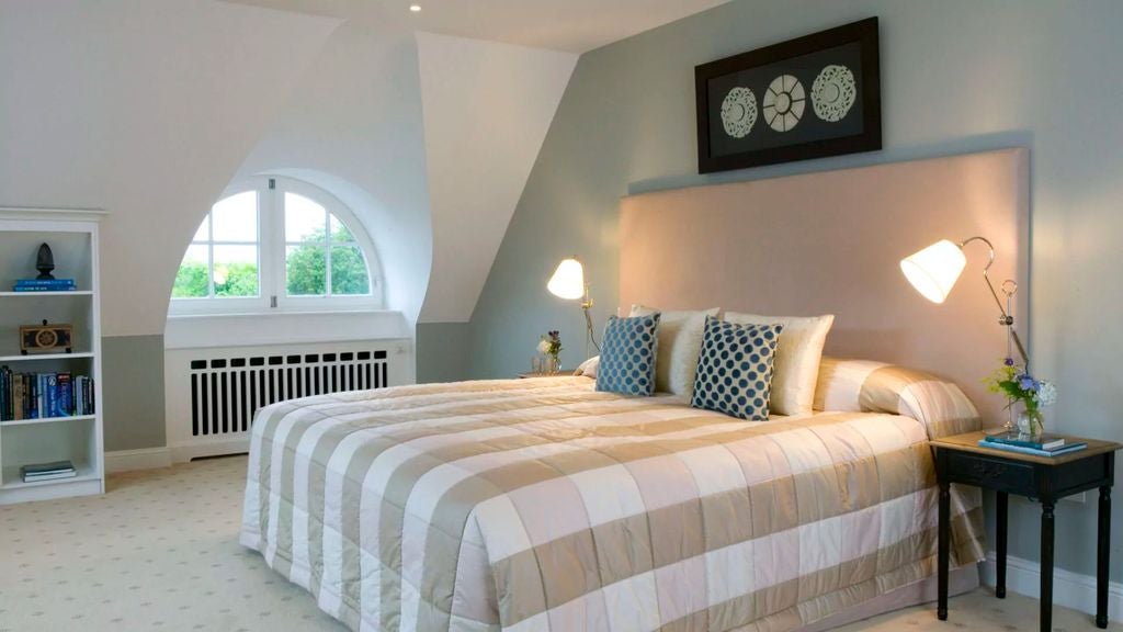 Elegant hotel room with panoramic bay windows, plush king bed, modern furnishings, and natural light overlooking Irish coastal waters