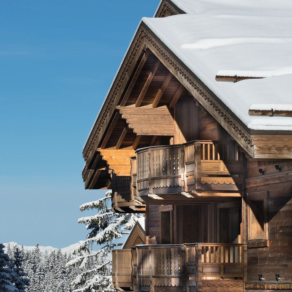 Luxurious alpine chalet at Six Senses Residences Courchevel, featuring modern design with wood and glass elements, snow-capped mountains in background