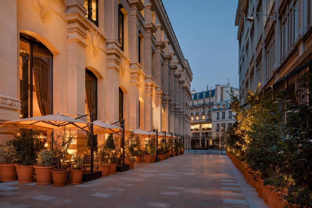 Elegant art-deco boutique hotel exterior with ornate gold signage, wrought iron balconies and cream stone facade in central Paris