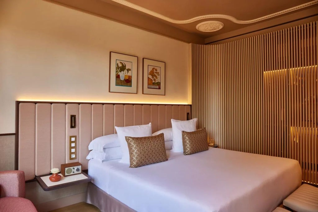 Elegant deluxe hotel room with modern minimalist design, featuring crisp white linens, sleek furniture, and panoramic city view in Barcelona's Grand Hotel Central.