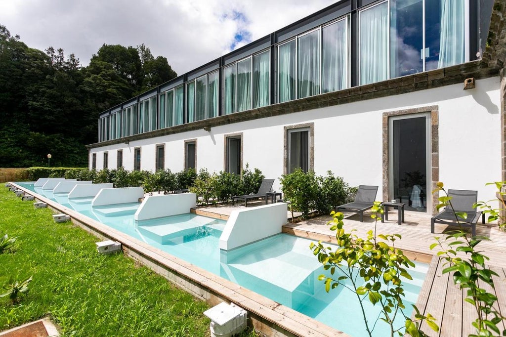 Elegant stone luxury hotel with arched windows and ornate balconies nestled in lush tropical gardens of São Miguel Island, Azores