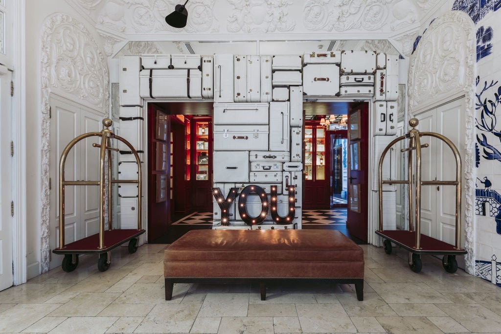 Art deco-inspired luxury hotel entrance with ornate blue doors, brass hardware, and classic European façade lit by vintage sconces