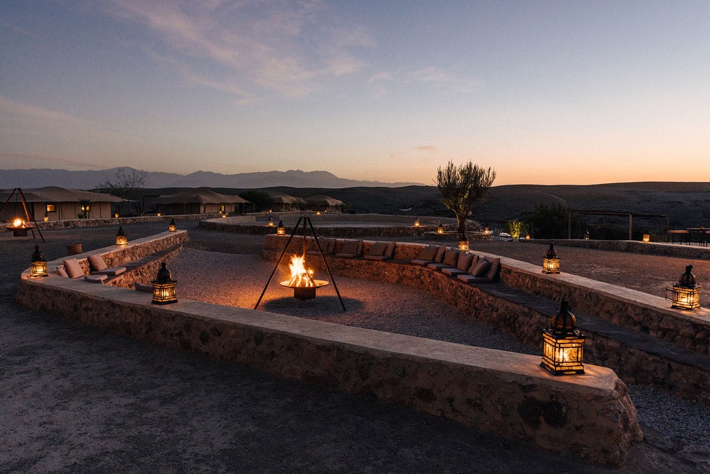 Luxurious desert camp tent with private pool overlooking vast Moroccan desert landscape, Agafay mountains in golden sunlight