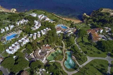 Luxurious coastal resort with infinity pool overlooking azure Atlantic waters, surrounded by lush tropical gardens at scenic Portuguese cliff-side location