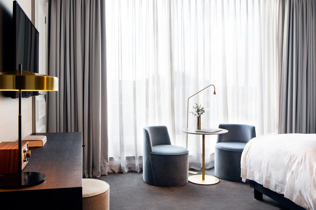 Elegant luxury hotel room with plush white bedding, sophisticated decor, and soft ambient lighting at Reylof Boutique Hotel in Belgium.