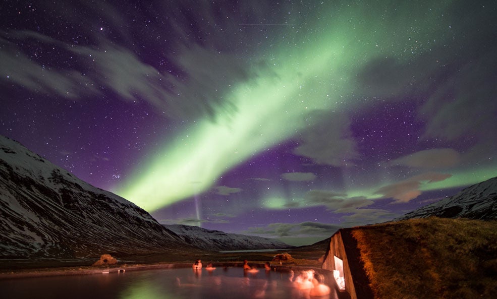 Luxurious Nordic lodge nestled in snow-covered Icelandic landscape, with floor-to-ceiling windows revealing dramatic mountain and winter terrain scenery