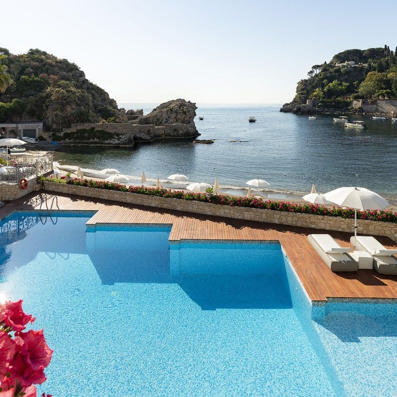 Elegant 5-star Mediterranean hotel with terraced balconies overlooking crystal-blue waters of Mazzaro Bay in Taormina, Sicily