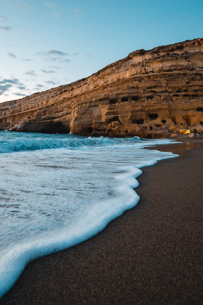 Mediterranean coastline with crystal-clear turquoise waters, white-washed buildings nestled in cliffs, and luxurious yachts in Crete's harbor