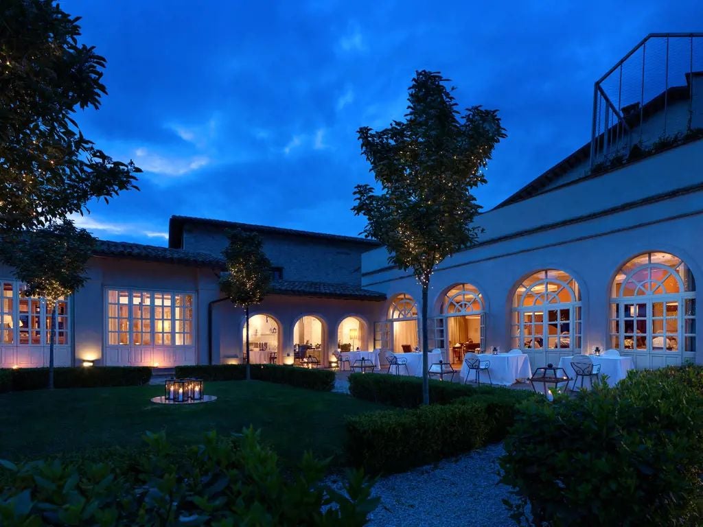 Elegant stone facade of historic Palazzo Seneca hotel in Norcia, Umbria, with warm terracotta tones and traditional Italian architectural details at dusk