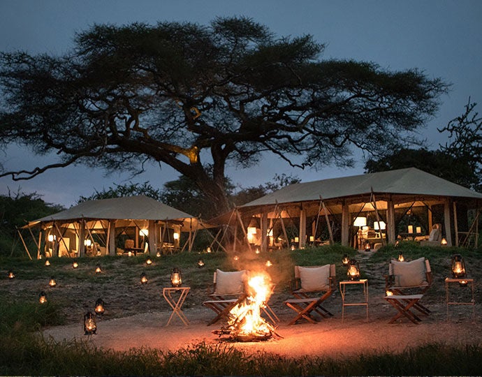 Private luxury tent at Mila Camp overlooking Tanzania savanna, featuring canvas walls, wooden deck, and panoramic wilderness views