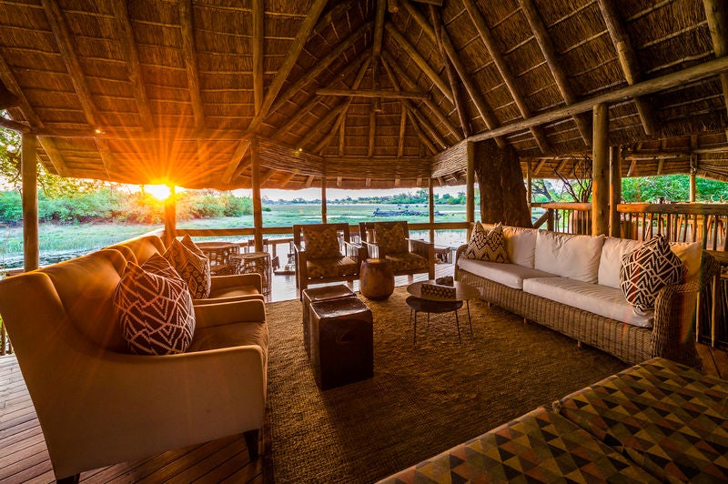 Elevated safari lodge overlooking Savuti Channel, featuring tented suites with private decks and plunge pools amid acacia trees