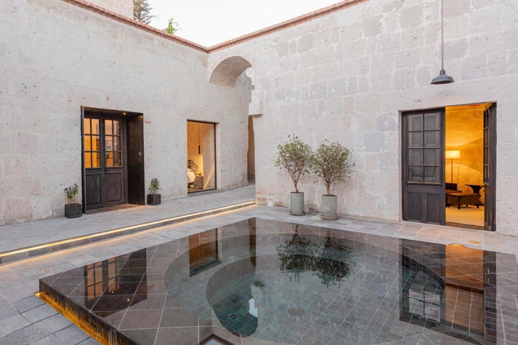 Luxurious colonial-style hotel with white stone arches, rustic wooden doors and elegant terracotta roof tiles in Arequipa, Peru