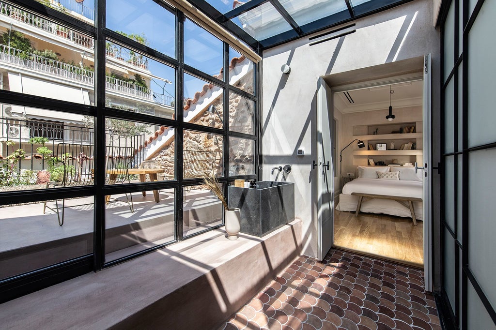 White luxury boutique hotel building in Athens with ornate iron balconies, tall arched windows, and neoclassical facade against blue sky